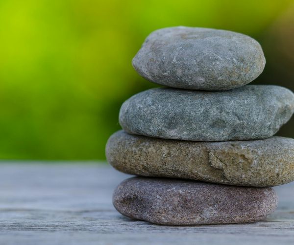 A stack of smooth stones balanced on a wooden surface.